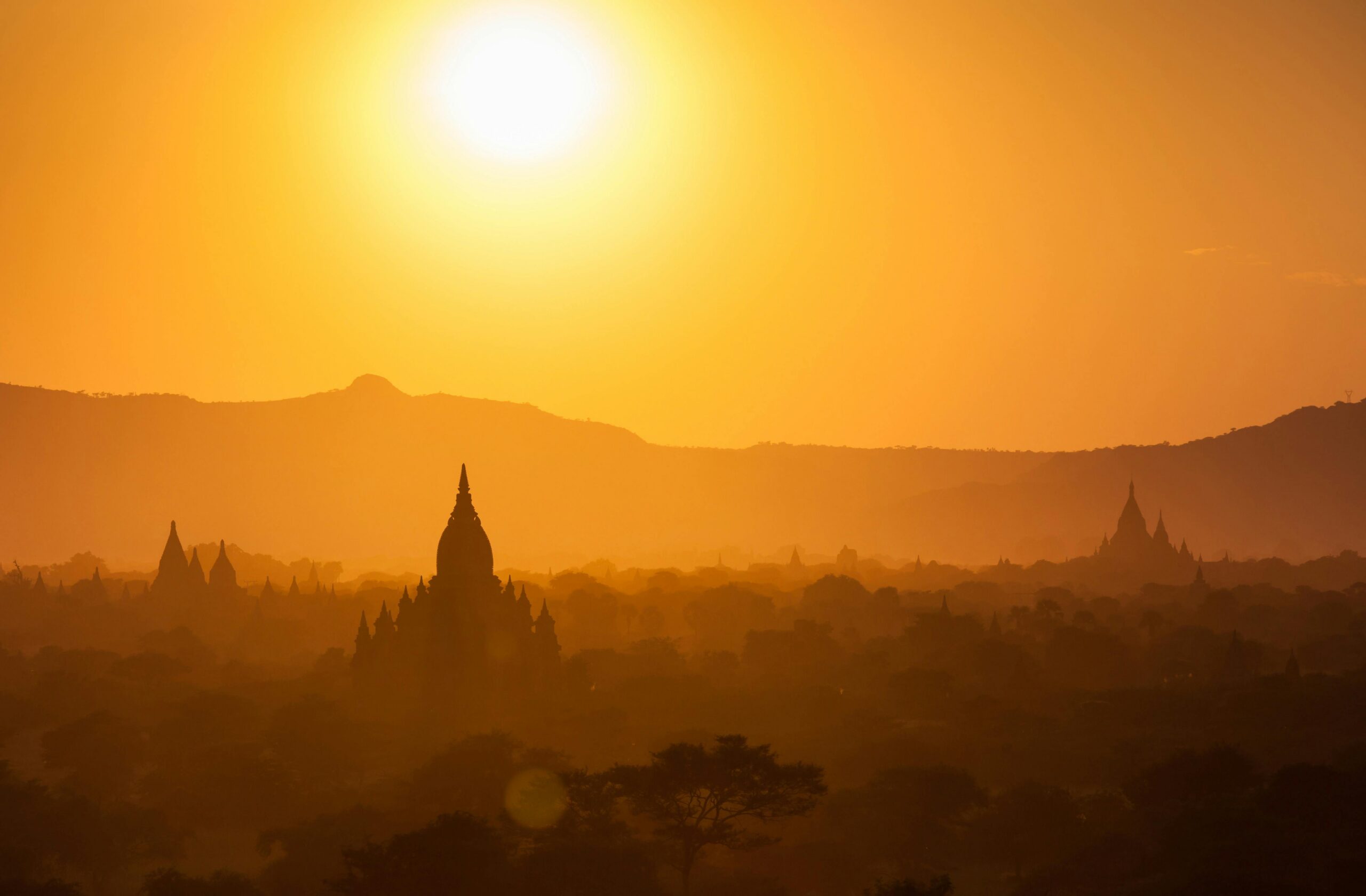 Silhouette of Bagan temples at sunset with golden skies and landscape.